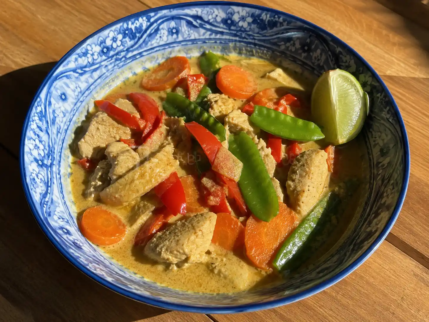 asiatisk gryta i skål med kokosmjölk, kyckling, paprika, morot och lime bredvid ris
