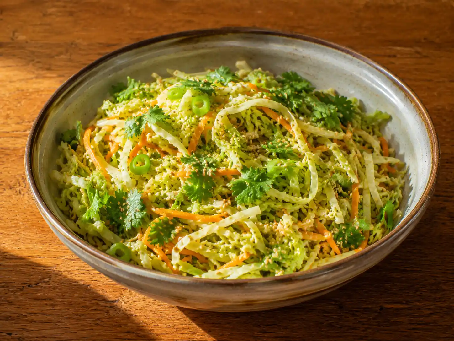asiatisk kålsallad i skål med strimlad vitkål, morot, koriander, sesam och blank lime-sojadressing