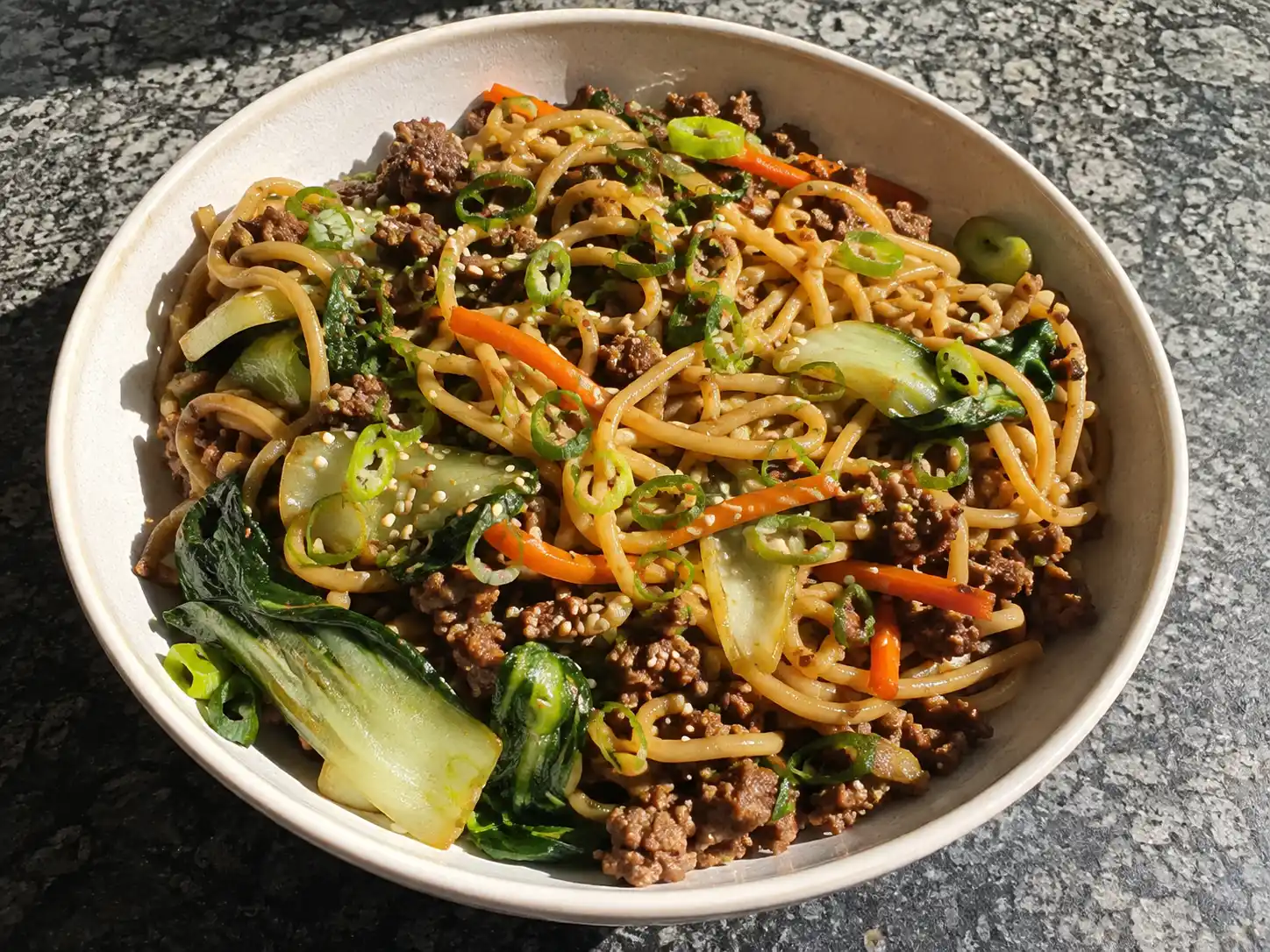 asiatisk köttfärs med nudlar i skål med brynt nötfärs, pak choi, morot, salladslök och sesam