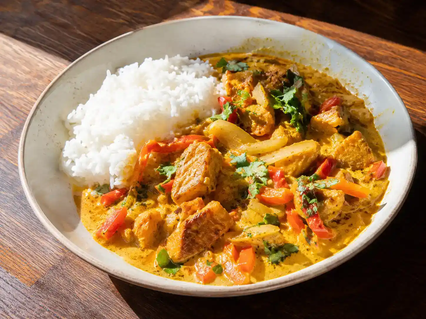 Asiatisk kycklinggryta med kokosmjölk, röd paprika och koriander serverad med nykokt jasminris
