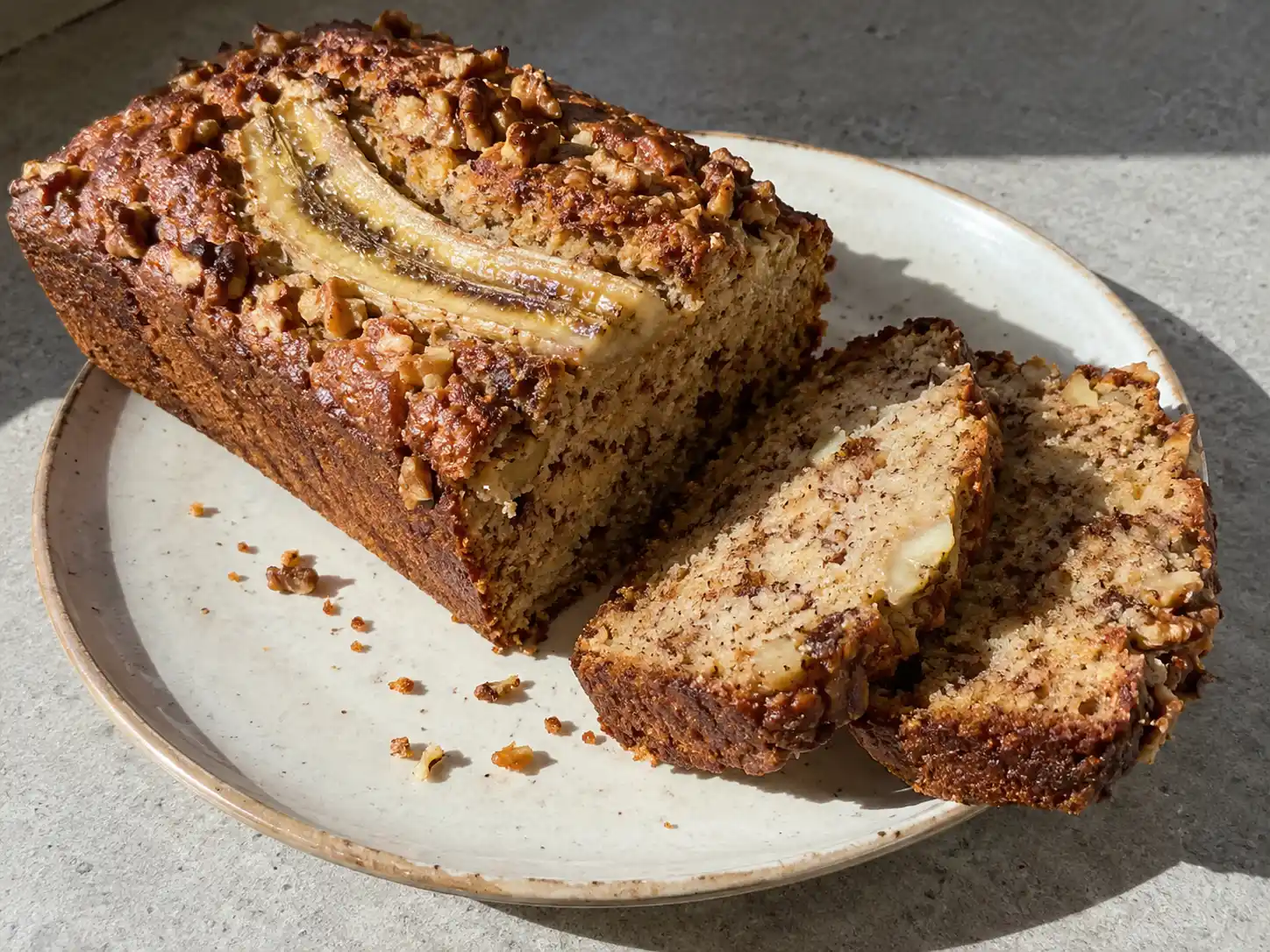 bananbröd glutenfritt i skivor med gyllene yta, saftig mitt, banan och hackade valnötter ovanpå
