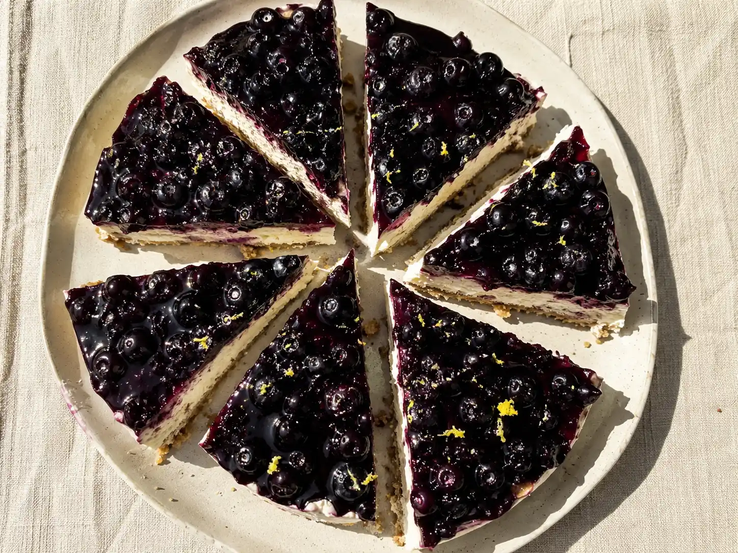 cheesecake med blåbär på tallrik med krämig fyllning, kexbotten och mörkblå topping