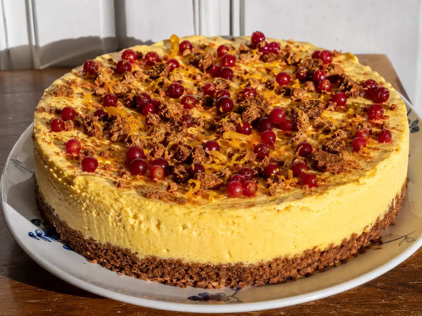 cheesecake saffran med gul krämig fyllning, pepparkaksbotten och lingon på ett fat