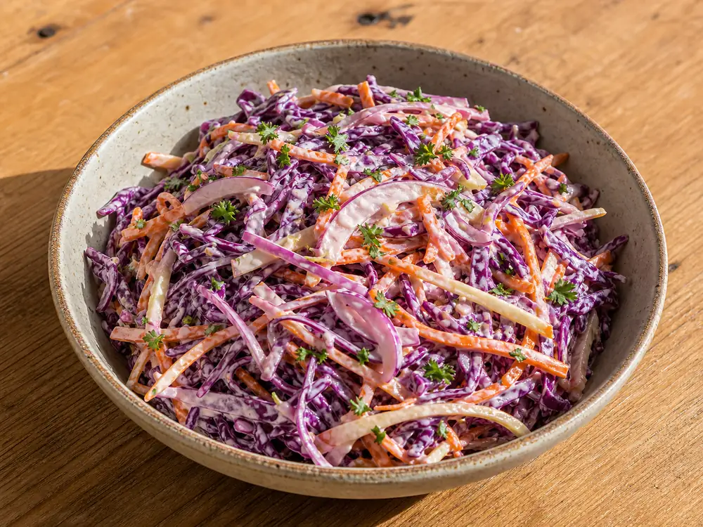 coleslaw rödkål i skål med krämig dressing, morot, äpple och finstrimlad kål