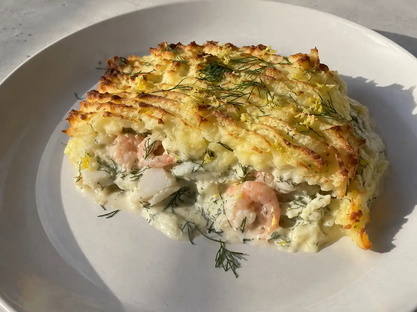 fiskgratäng med räkor med gyllene potatismos, torsk, krämig dillsås och färska räkor på toppen