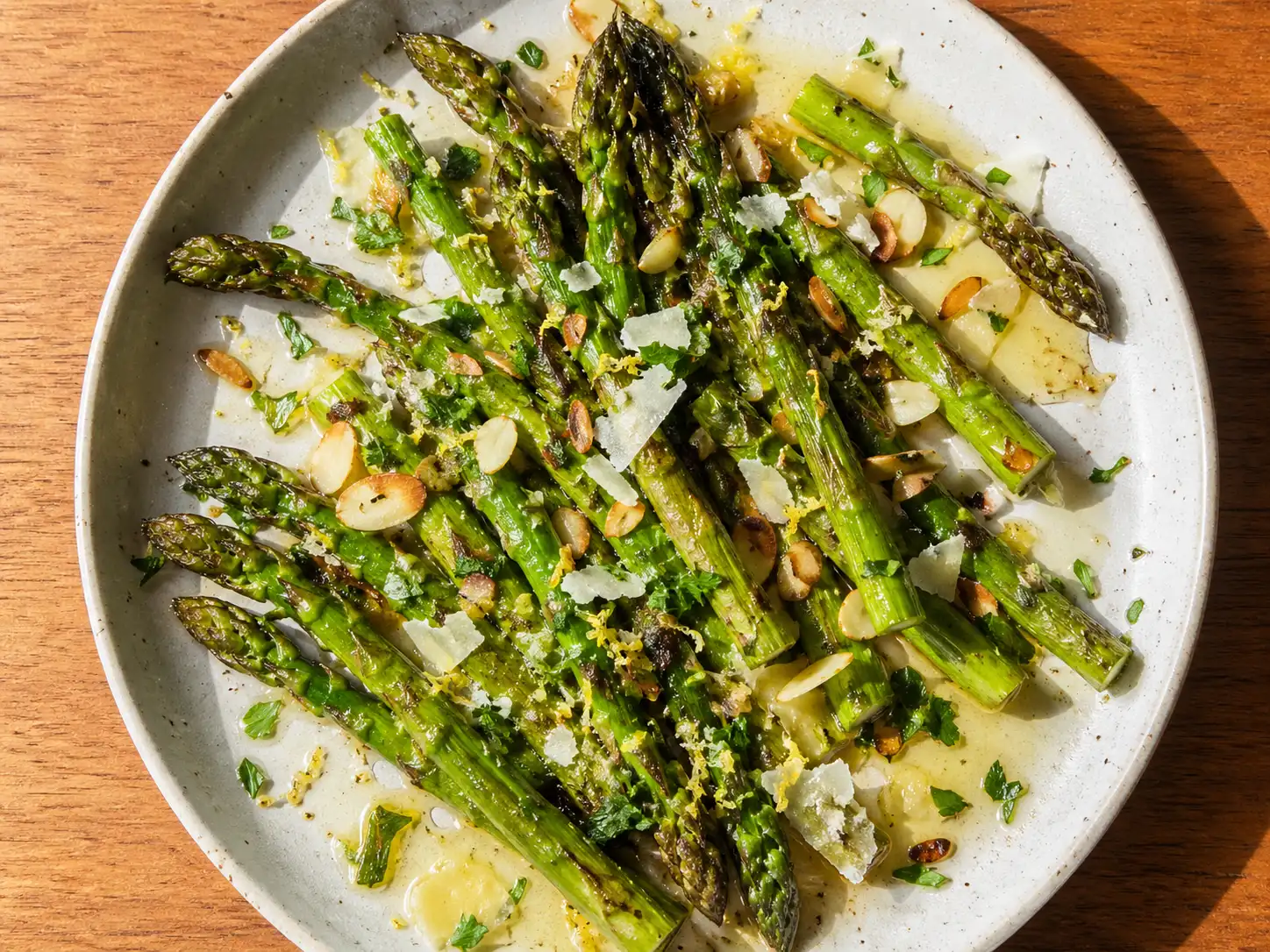 förrätt med sparris på tallrik med parmesan, citron och brynt smör över grön sparris
