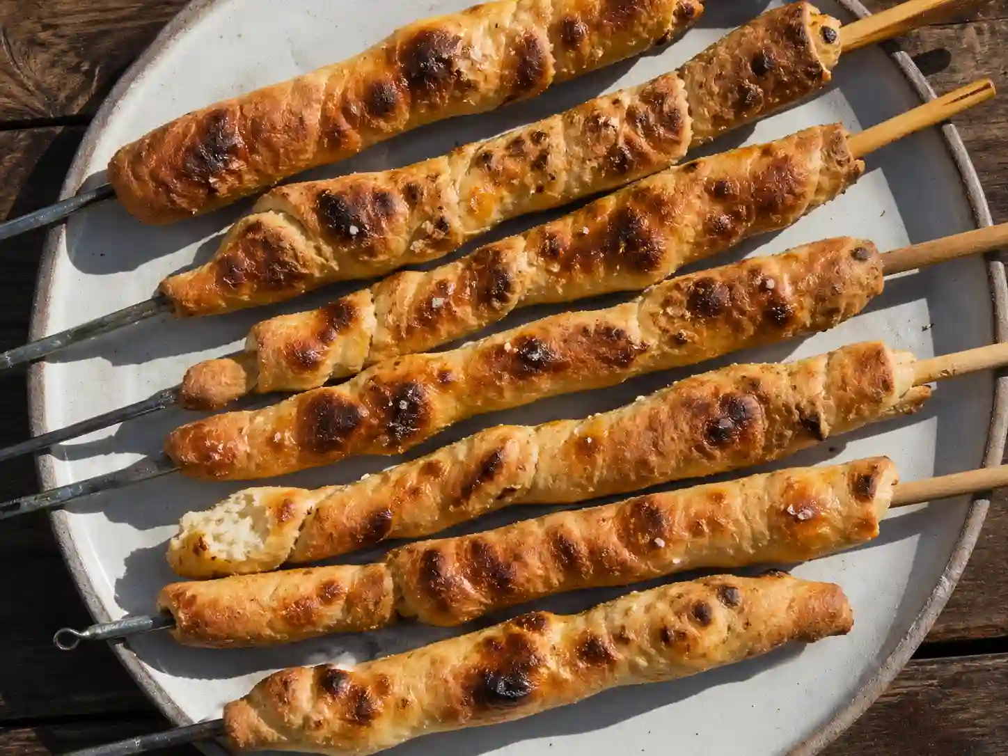 glutenfritt pinnbröd på pinnar med gyllene yta, mörka grillfläckar och mjuk insida på enkel tallrik