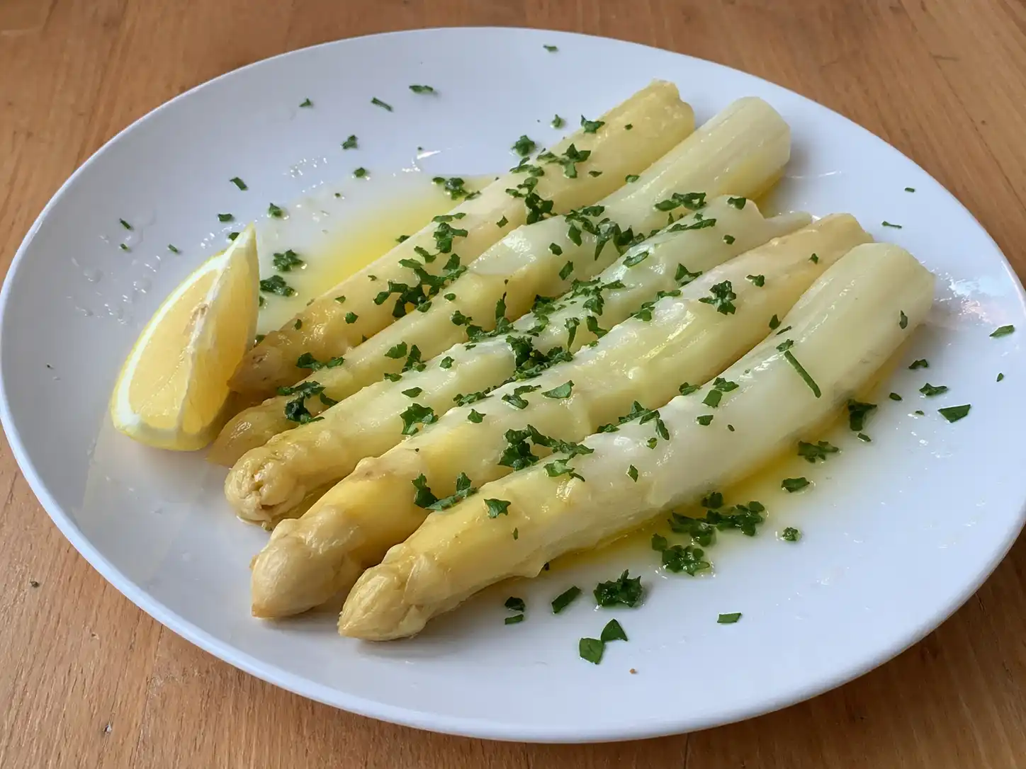 koka vit sparris serverad mör och blank med smör, citron och lite persilja på en enkel tallrik