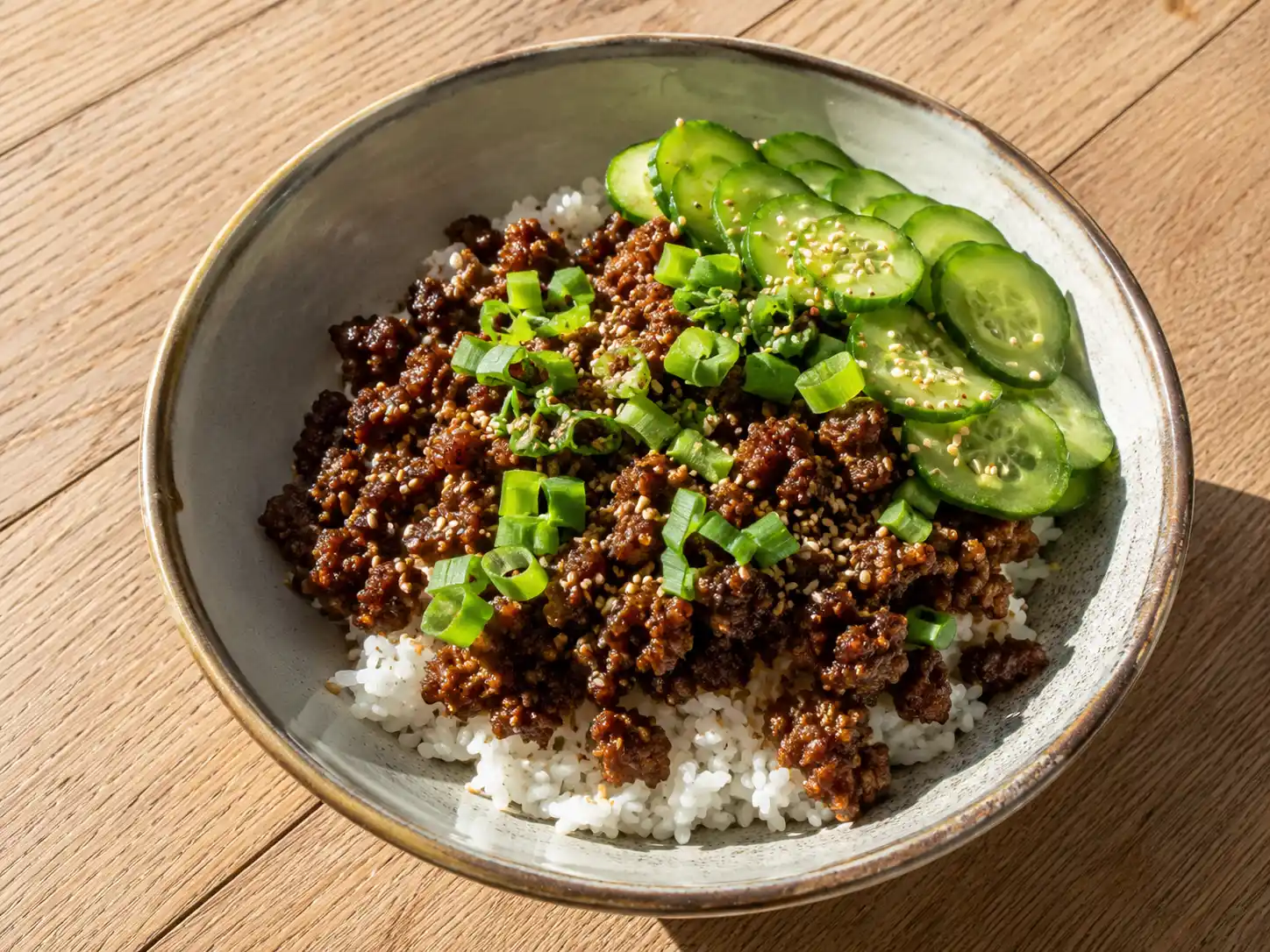koreansk köttfärs med glansig sojasås, ris, gurka, salladslök och rostade sesamfrön i skål