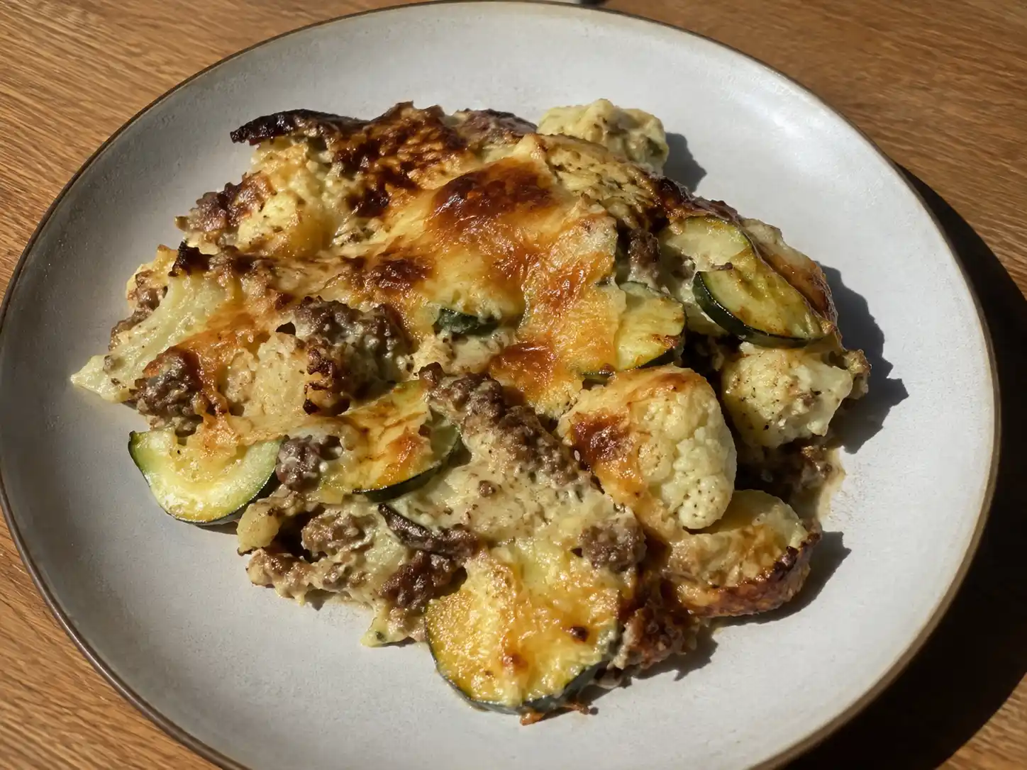 lchf köttfärs som krämig gratäng med blomkål, zucchini och gyllene smält ost på en enkel tallrik