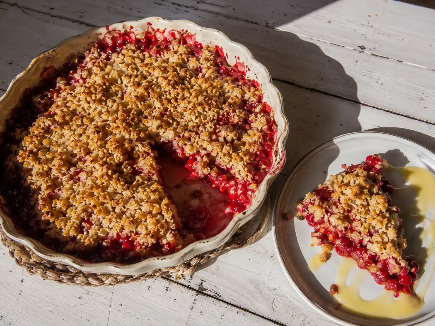 paj med röda vinbär i pajform med knäckigt havresmul och röd, bubblig fyllning under gyllene yta