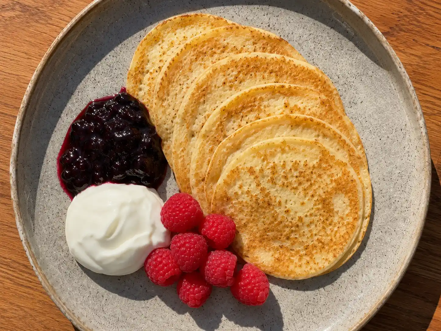 pannkakor med vita bönor i liten stapel med sylt, bär och gyllene stekyta på tallrik