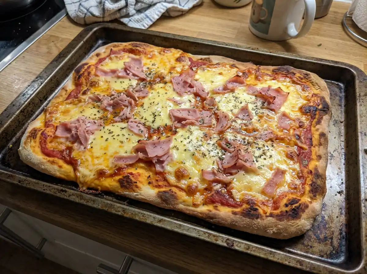 pizza recept med gyllene ost, tomatsås och strimlad skinka på krispig botten, nygräddad i ugn