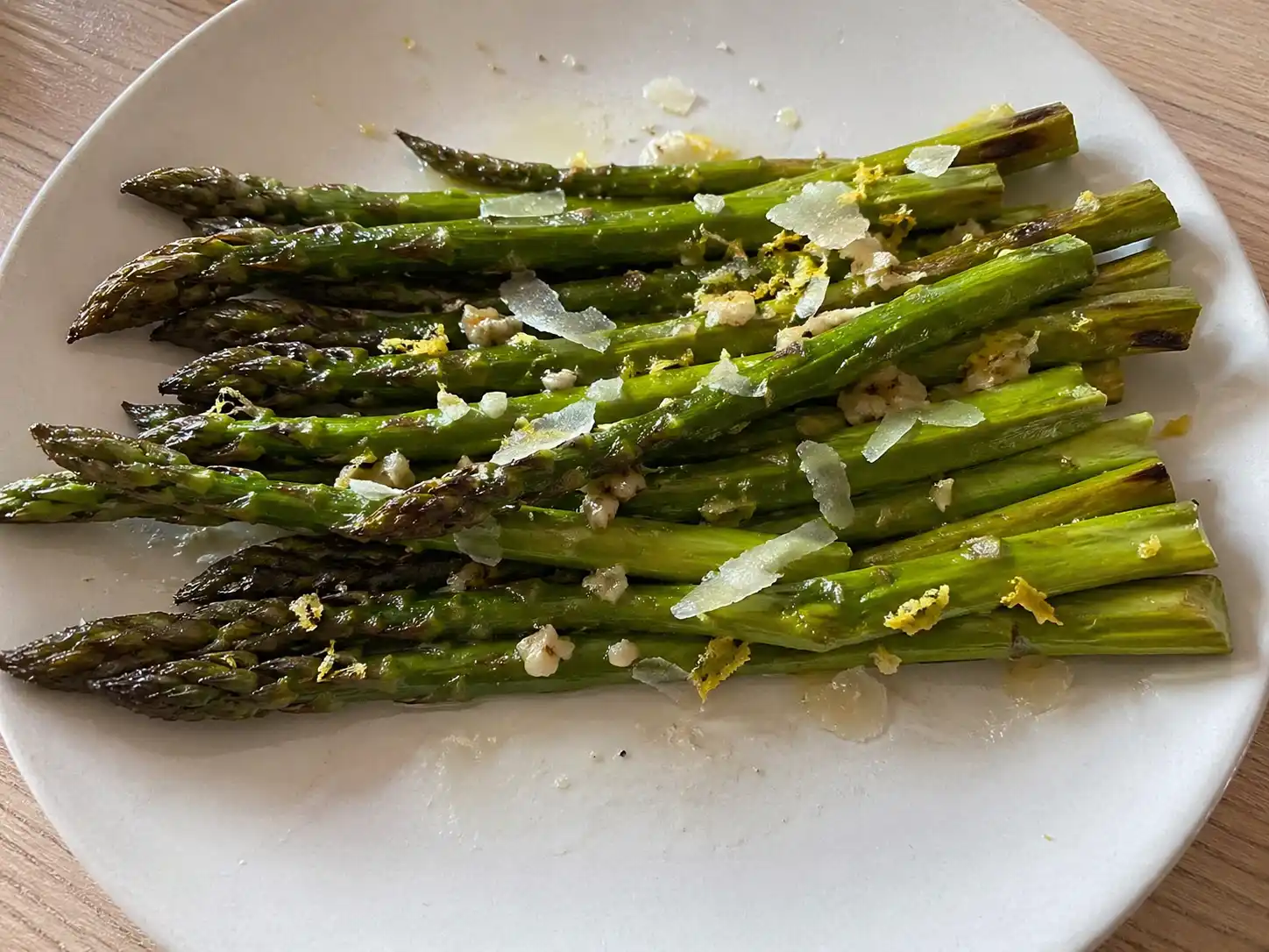 sparris i ugn med citron, vitlök och hyvlad parmesan på enkel tallrik