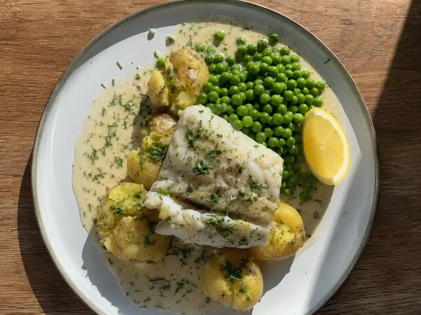 torskrygg med vitvinssås med pressad potatis, dill och gröna ärter på en enkel middagstallrik