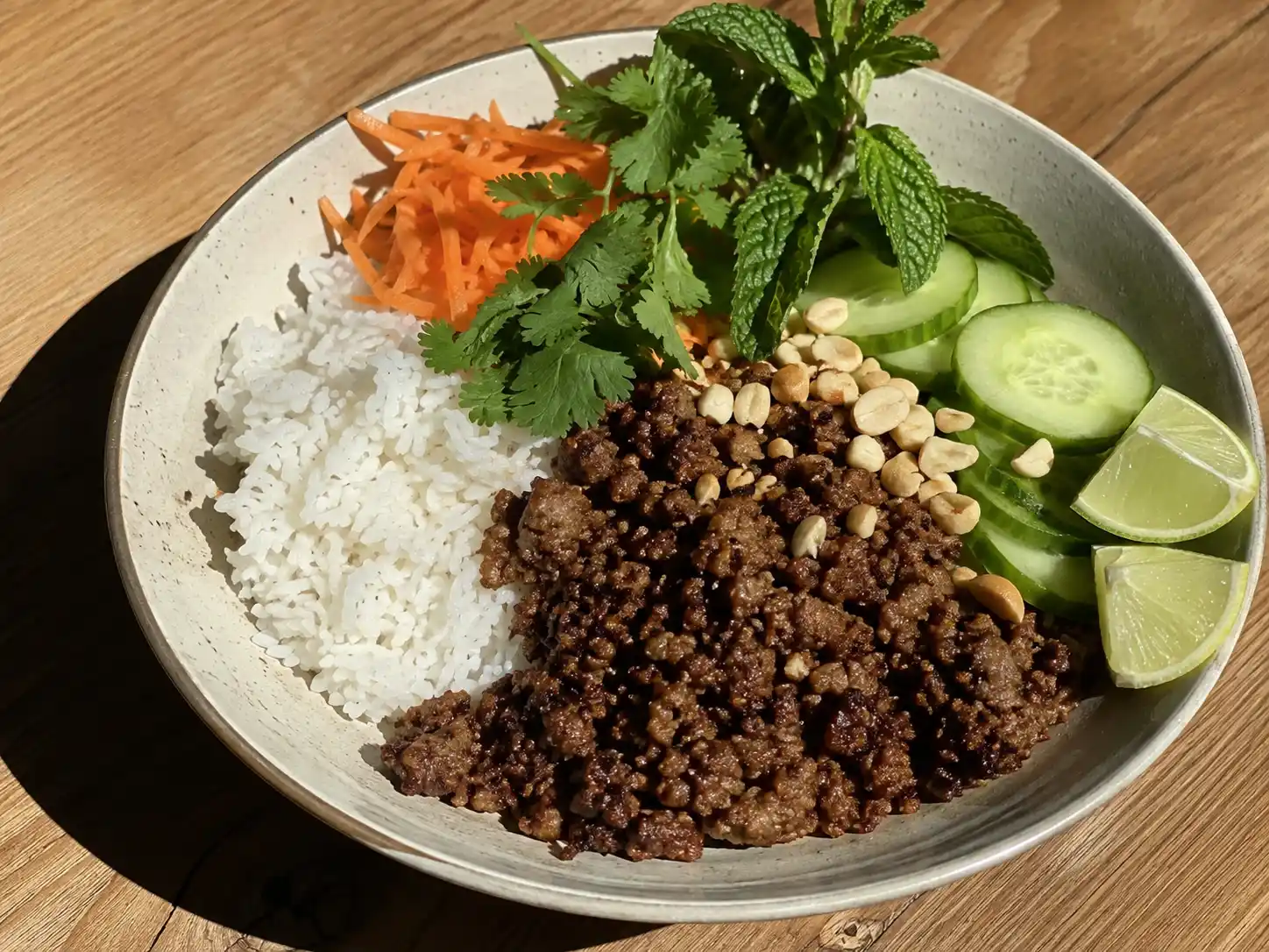 vietnamesisk köttfärs med ris, lime, gurka, morot, koriander och gyllenbrun färs i skål