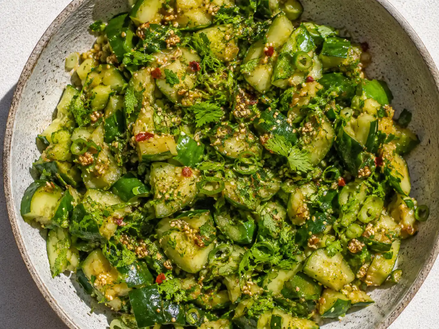 asiatisk gurka i skål med krossade gurkbitar, sesamfrön, chili och salladslök