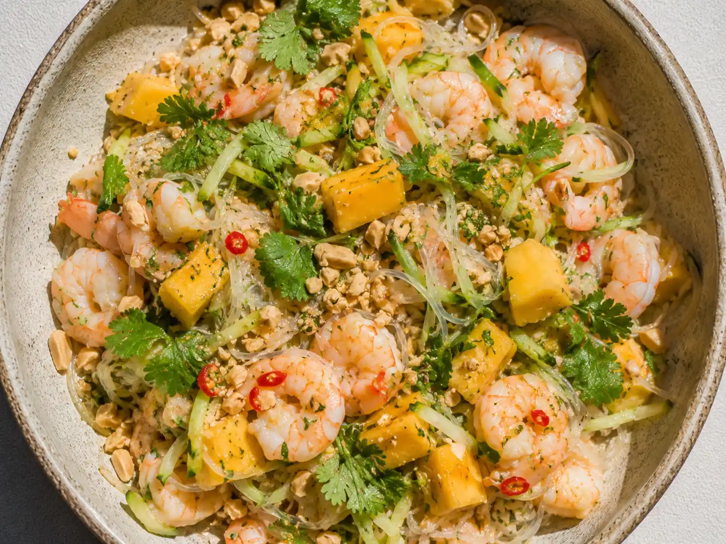 asiatisk räksallad med glasnudlar, räkor, mango och krispiga grönsaker på ett stort fat