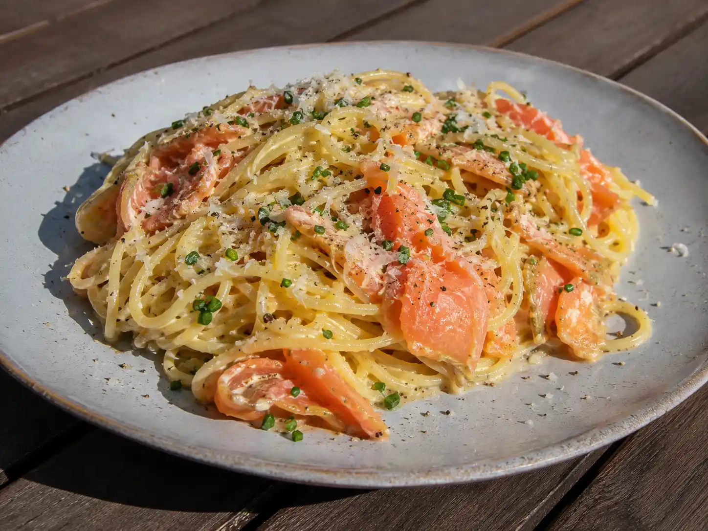 carbonara med lax med krämig spaghetti, kallrökt lax, parmesan, citron och gräslök på tallrik