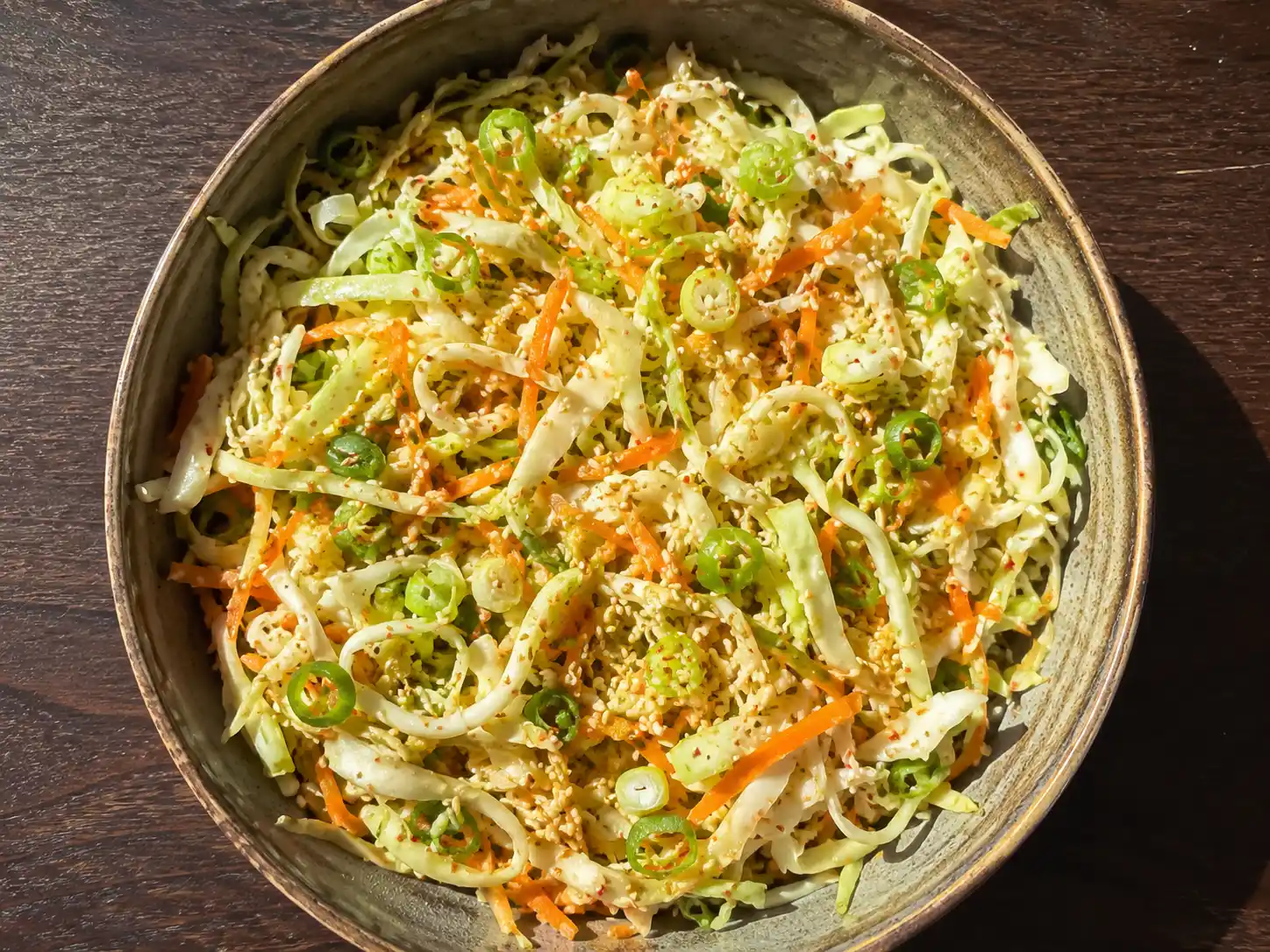 asiatisk vitkålssallad med morot, salladslök och sesam i skål med krispig yta och blank dressing