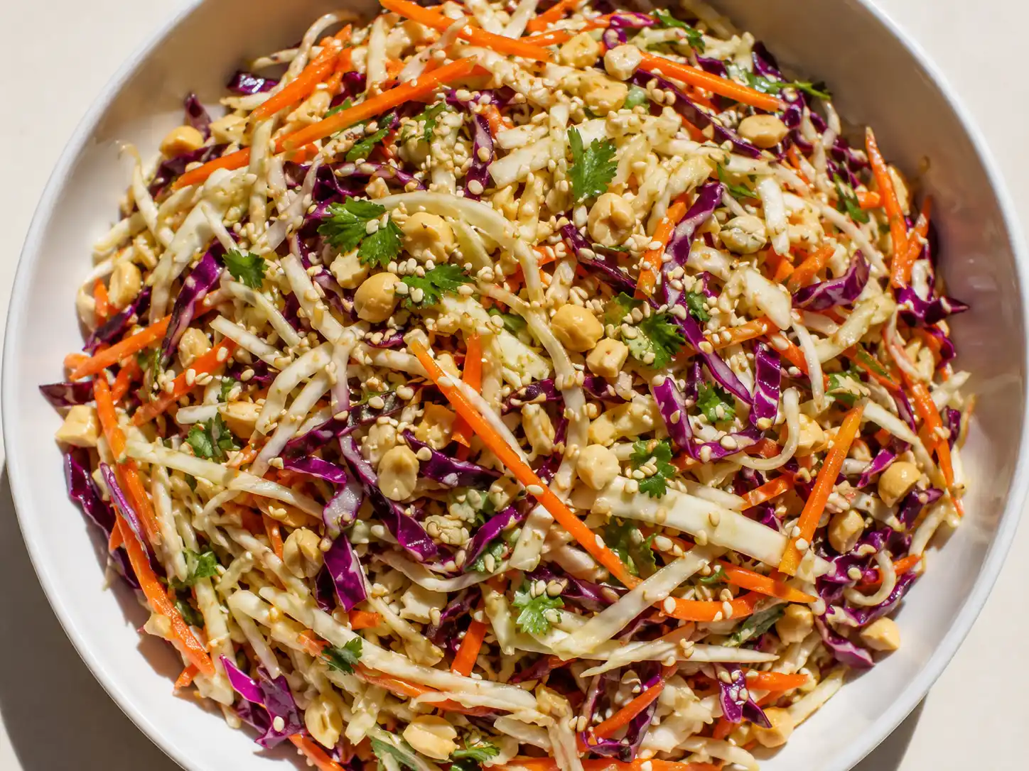kålsallad asiatisk i skål med strimlad kål, morot, sesamfrön, koriander och jordnötter