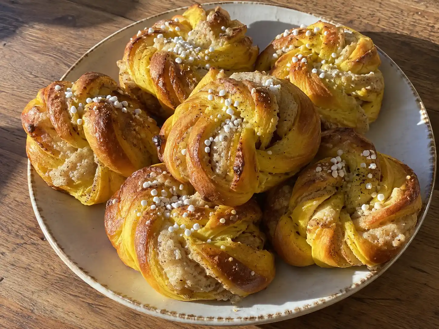 lussebullar med fyllning med gyllene saffransdeg, mandelmassa och pärlsocker på en enkel tallrik