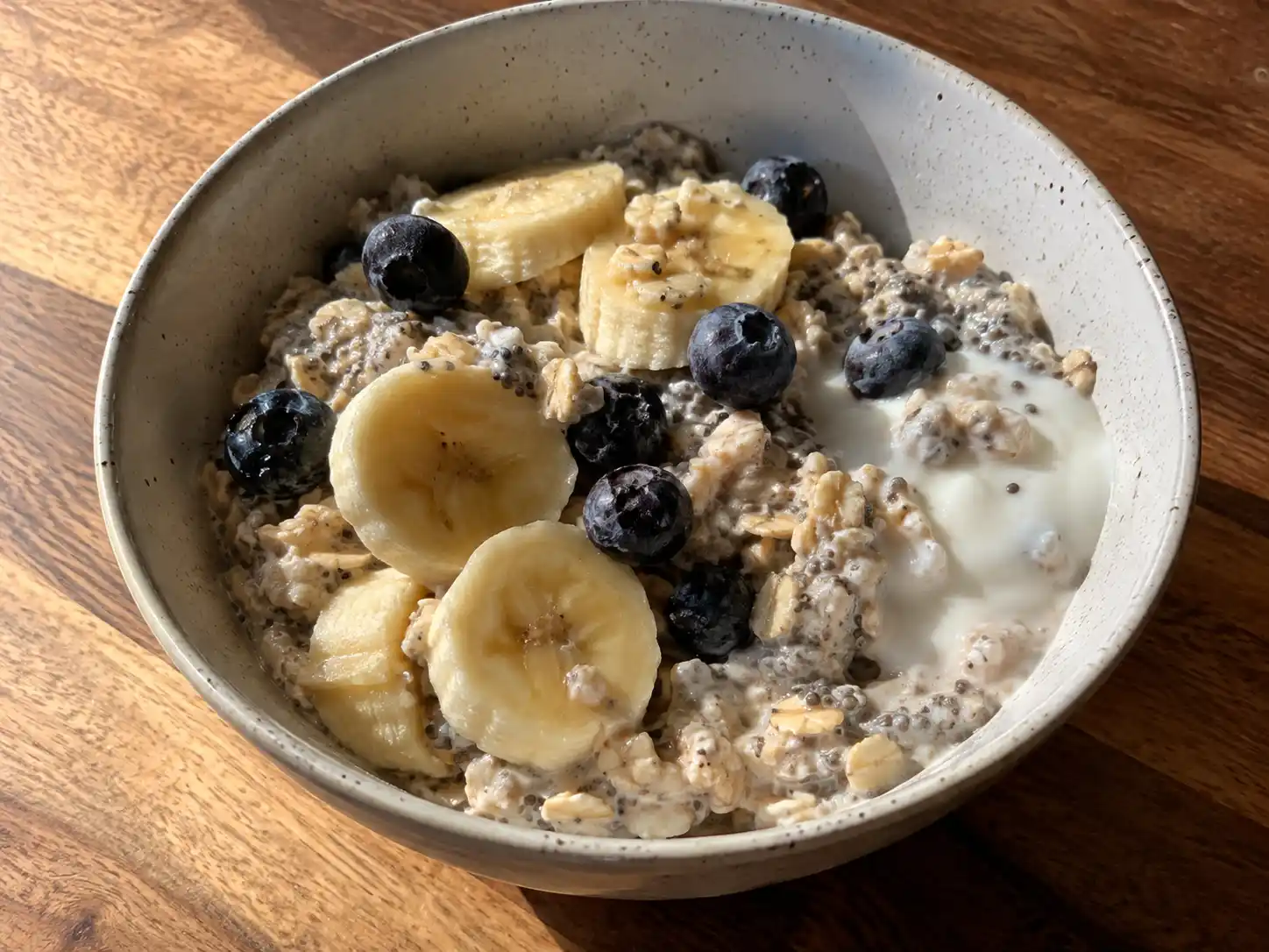 overnight oats med chiafrön i skål med bananskivor, blåbär och tydligt krämig havregrynsbas