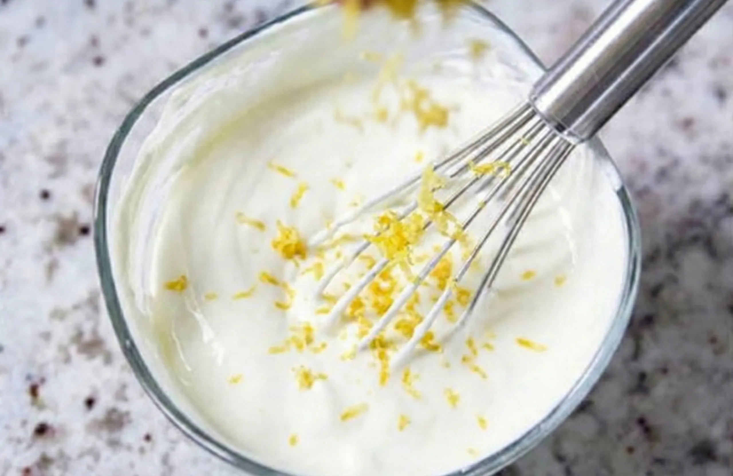 Närbild på när citronskal rivs direkt ner i en bunke med dessertmet.