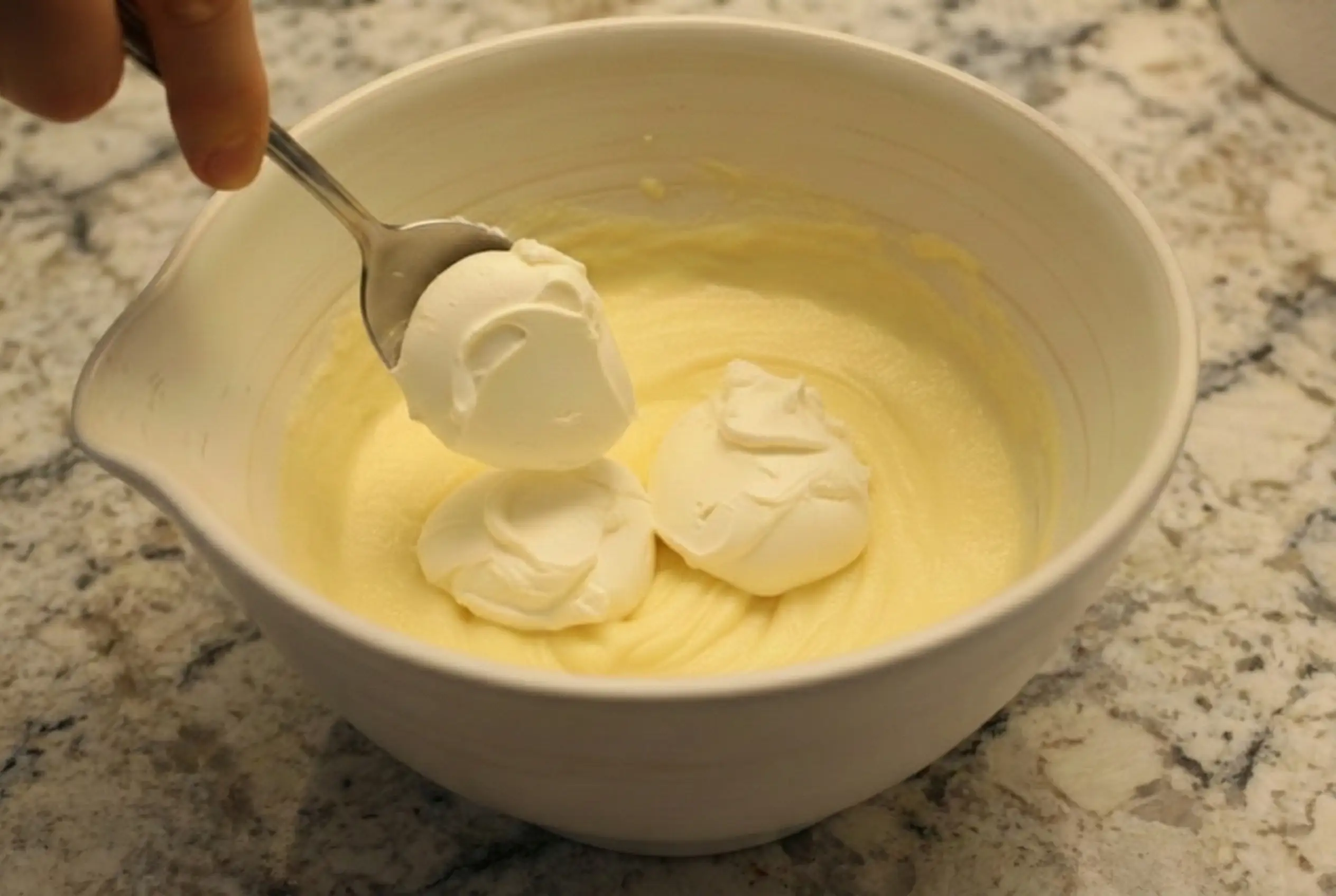 Krämig färskost som rörs ner i äggulesmeten tills blandningen är helt slät och jämn