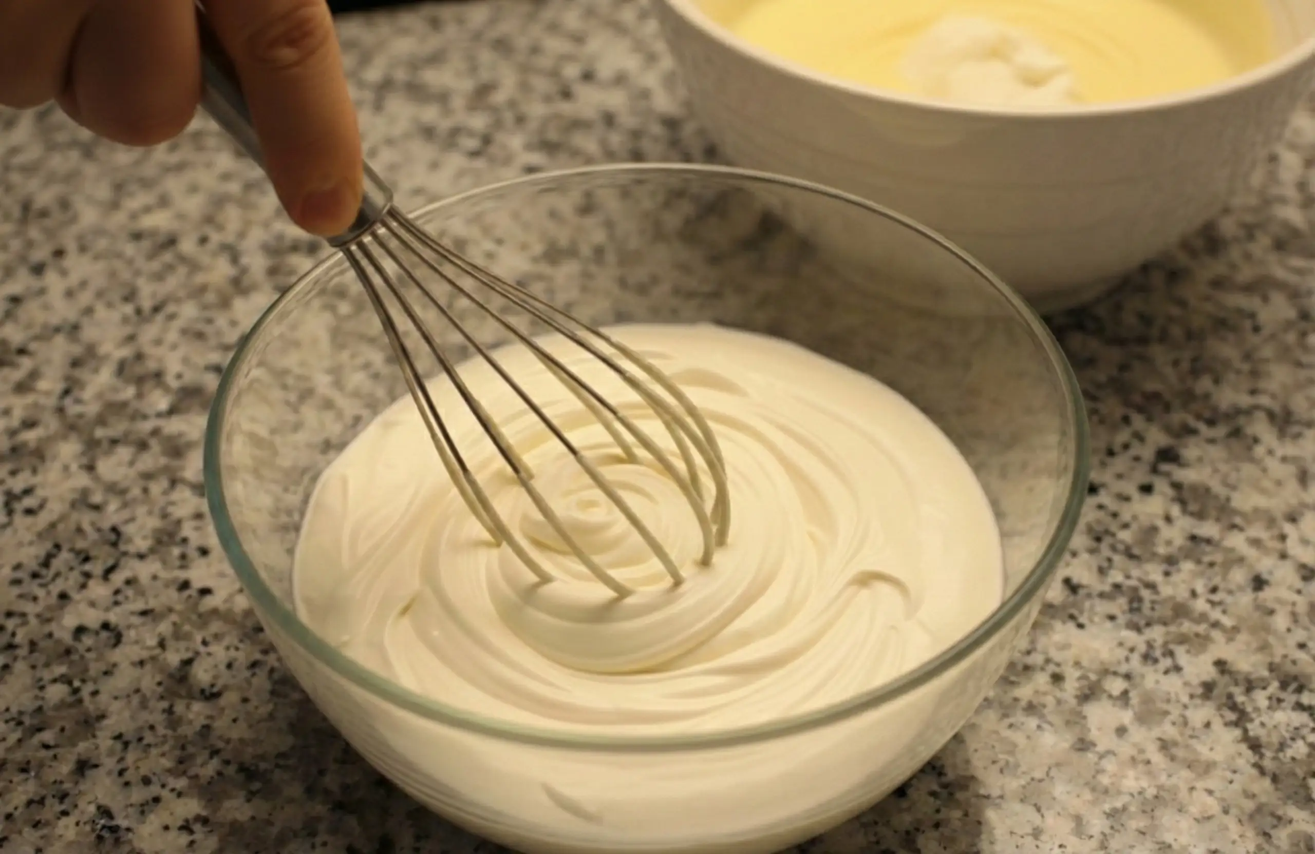 Vispad grädde med lagom fast konsistens som försiktigt vänds ner i ostsmeten med en slickepott.